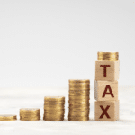 picture with stacked coins and blocks with the word tax on them